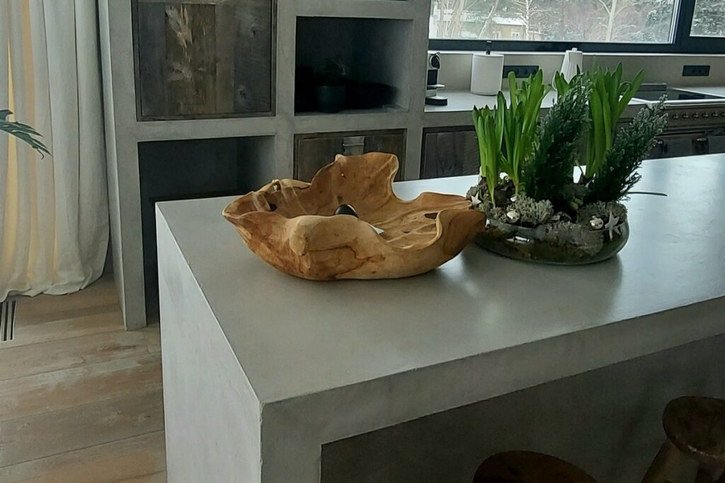 Fronty mebli kuchennych wykończone mikrocementem w jednolitym odcieniu szarości. Mikrocement na elementach mebli w kuchni pozwala uzyskać industrialny i sp&oacute;jny efekt.