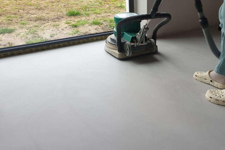 Szlifowanie podłogi z mikrocementu polerko szlifierką pokazuje pracę na większej powierzchni, kt&oacute;ra pozwala uzyskać odpowiednią gładkość i przygotować posadzkę do zabezpieczenia.