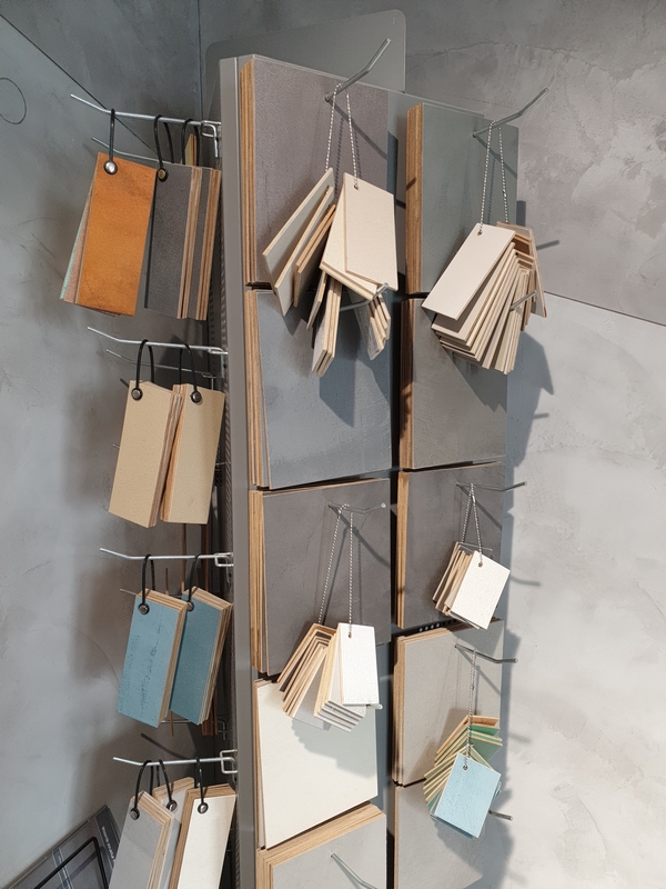 R&oacute;żne pr&oacute;bki mikrocementu prezentujące odcienie szarości, beżu i grafitu na powierzchniach testowych. Takie pr&oacute;bki pozwalają sprawdzić rzeczywisty efekt kolorystyczny mikrocementu.