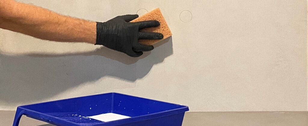 Nakładanie impregnatu na mikrocement pokazuje etap wstępnego zabezpieczenia, kt&oacute;ry ogranicza chłonność i przygotowuje powierzchnię pod końcowe warstwy lakieru poliuretanowego.