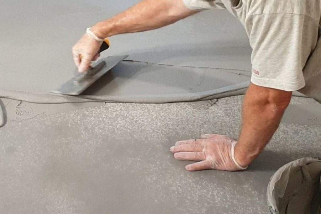 Schemat lub prezentacja etap&oacute;w, jak wykonana jest podłoga z mikrocementu w systemie warstwowym. Pokazuje kolejność prac przed uzyskaniem gotowej posadzki z mikrocementu.