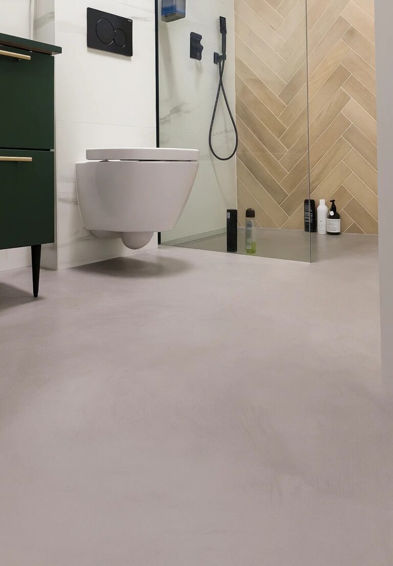 Podłoga w łazience z mikrocementu MEDIUM FAST pokazuje jednolitą powierzchnię w strefie wilgotnej, kt&oacute;rą wybiera się zamiast płytek, gdy liczy się sp&oacute;jny wygląd i brak fug.