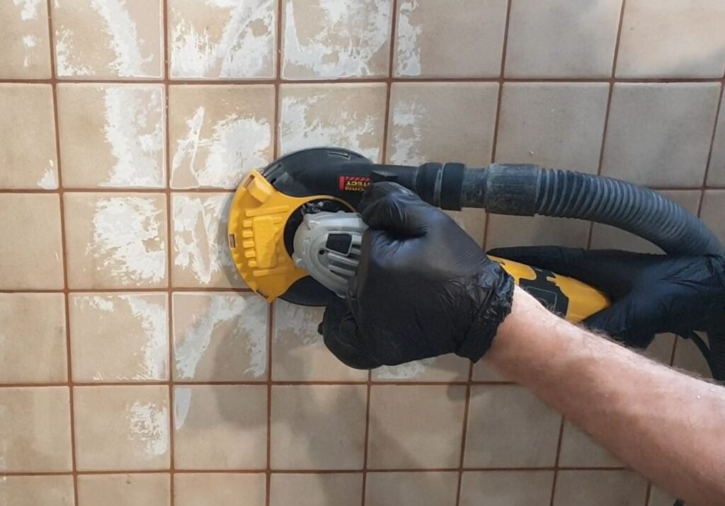 Przygotowanie płytek pod mikrocement pokazuje szlifowanie i matowienie podłoża, kt&oacute;re jest konieczne, gdy chcesz położyć mikrocement na stare kafle bez skuwania i poprawić przyczepność warstw.