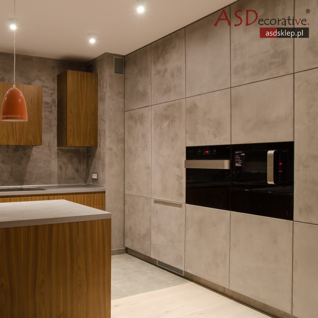 Fragment kuchni z mikrocementem na ścianie roboczej oraz blacie w sp&oacute;jnej kolorystyce. Takie zastosowanie mikrocementu w kuchni podkreśla nowoczesny charakter wnętrza.