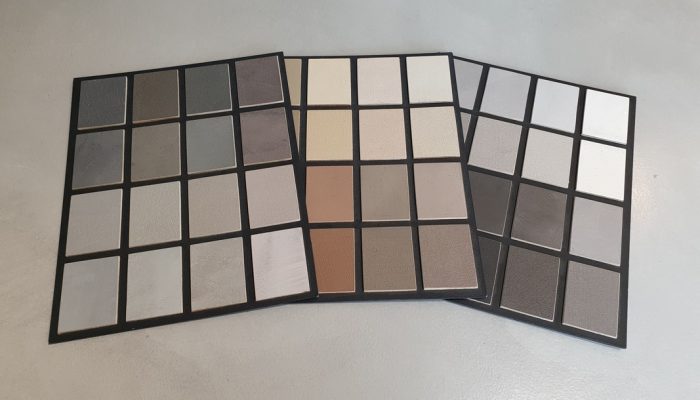 Paleta kolorów mikrocementu prezentująca różne odcienie i struktury materiału w formie próbek. Kolorystyka mikrocementu pozwala dopasować wykończenie powierzchni do stylu aranżacji wnętrza.