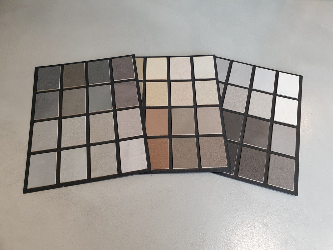 Paleta kolor&oacute;w mikrocementu prezentująca r&oacute;żne odcienie i struktury materiału w formie pr&oacute;bek. Kolorystyka mikrocementu pozwala dopasować wykończenie powierzchni do stylu aranżacji wnętrza.