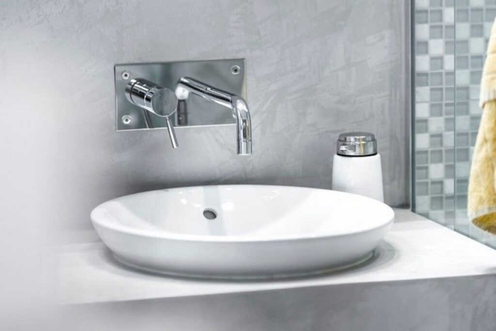 Zabudowa meblowa w łazience wykończona mikrocementem w jasnej kolorystyce. Meble z mikrocementu dobrze sprawdzają się w strefach narażonych na wilgoć.