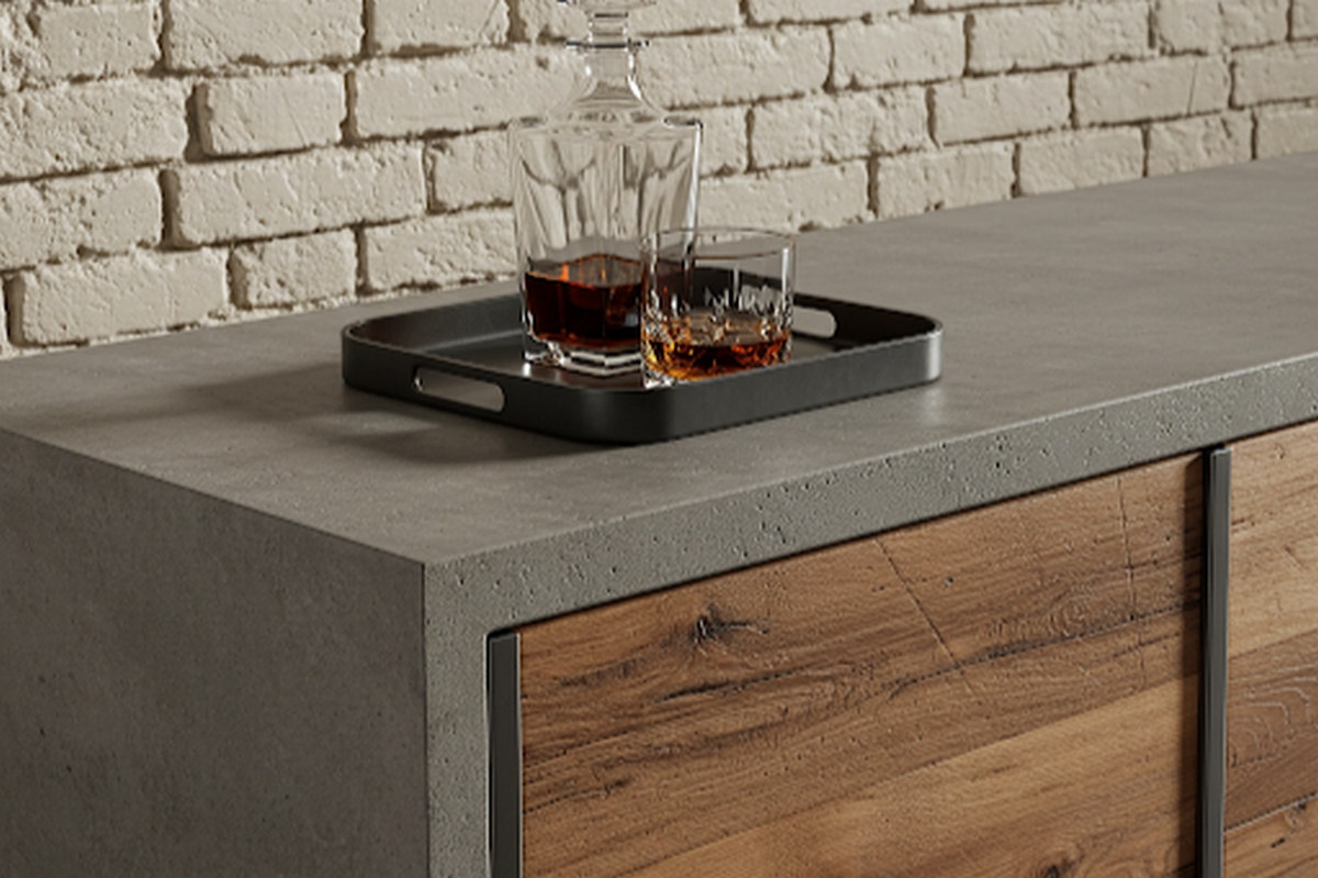 Blat meblowy pokryty mikrocementem w połączeniu z frontami w kolorze naturalnego drewna. Przy aplikacji mikrocementu na meblach zazwyczaj nie stosuje się warstw podkładowych, jeśli powierzchnia jest odpowiednio przygotowana.