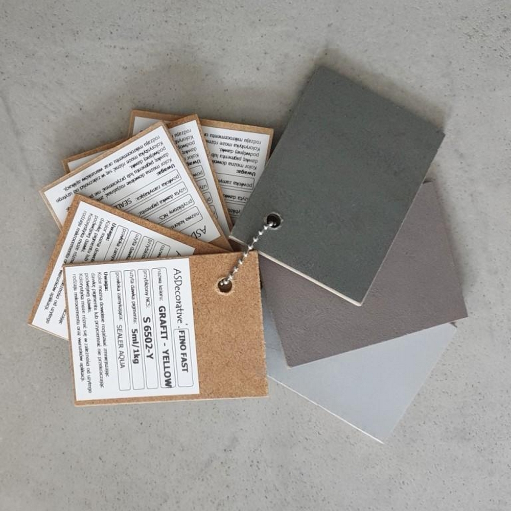 Wzornik kolor&oacute;w mikrocementu FAST w formie pr&oacute;bek zawieszonych na metalowym łańcuszku. Paleta pokazuje r&oacute;żne odcienie, kt&oacute;re można uzyskać podczas barwienia mikrocementu pigmentem.