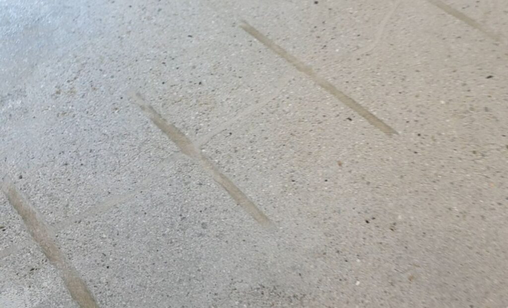 Naprawa pęknięcia podłoża przy użyciu żywicy i metalowych klamer przed ponowną aplikacją mikrocementu. Tego typu renowacja pozwala przygotować powierzchnię do dalszych prac wykończeniowych.