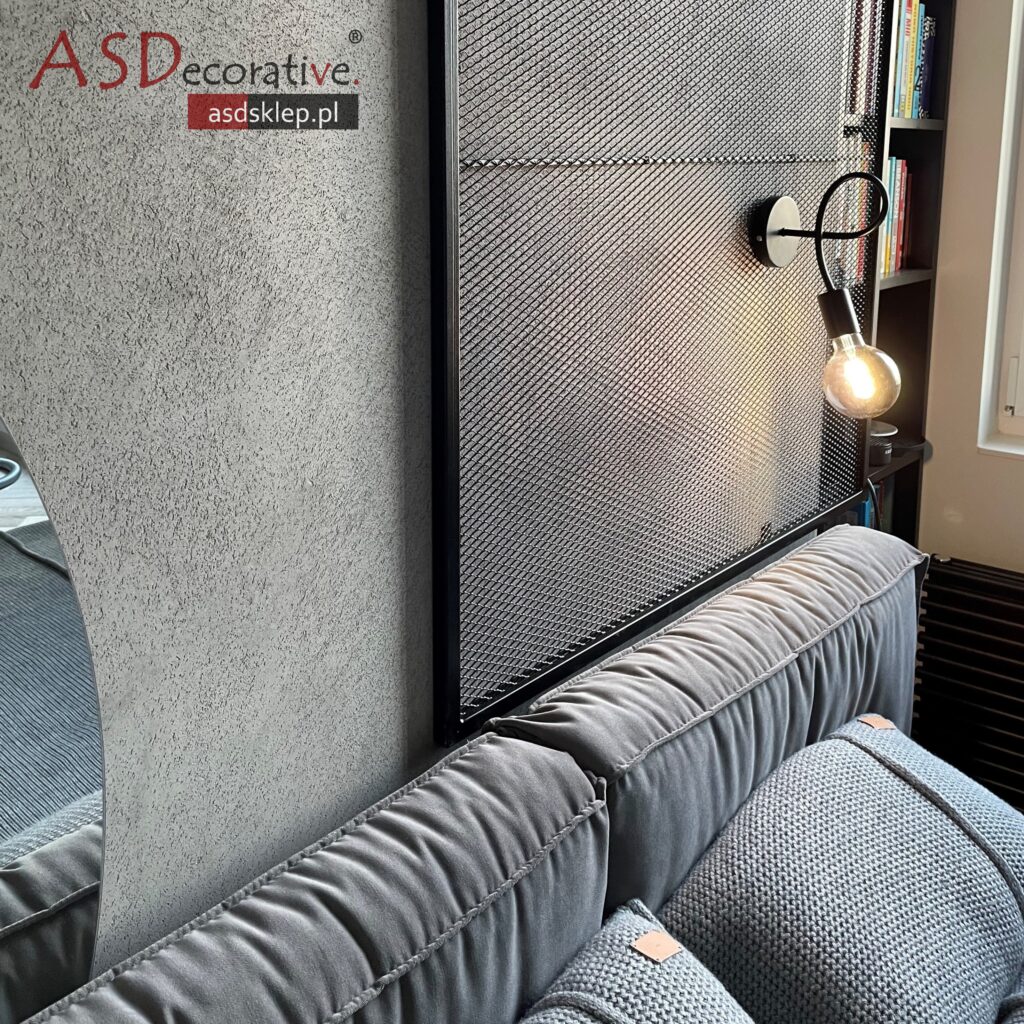 Zbliżenie na strukturę mikrocementu widoczną na ścianie w suchym pomieszczeniu. Mikrocement na ścianie pozwala uzyskać efekt betonu lub tynku dekoracyjnego.